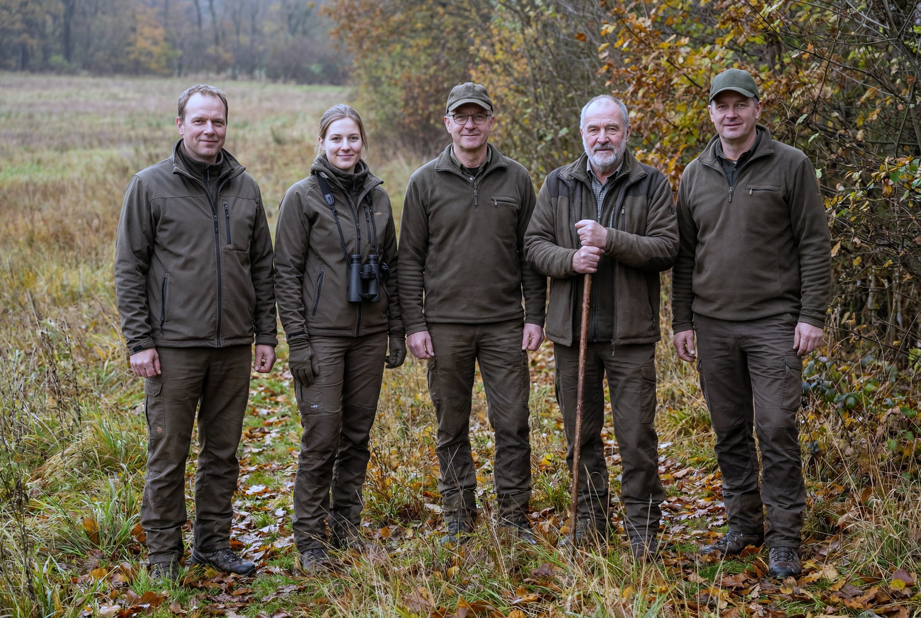 Drei Jäger in herbstlicher Landschaft